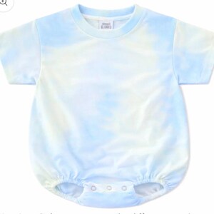 Może przedstawiać: Kr&oacute;tkoręki pajacyk niemowlęcy w jasnoniebiesko-biały wz&oacute;r tie-dye. Ubranko posiada okrągły dekolt, metkę z napisem simpli BLANKS oraz trzy metalowe zatrzaski w kroku. Otwory na nogi są wykończone elastyczną gumką.