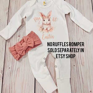 K&ouml;nnte beinhalten: Wei&szlig;er lang&auml;rmliger Baby-Strampler mit einem rosa Hasen-Motiv und dem Text "My 1st Easter". Ein rosa Schleifen-Stirnband ist ebenfalls enthalten. Der Text "Noruffles Romper Sold Separately in Etsy Shop" ist unter dem Motiv gedruckt.