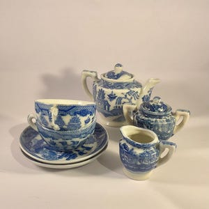 Può includere: Una tazza di ceramica bianca con manico nero e la scritta "But First, Coffee" in grassetto nero. La tazza è piena di un liquido scuro, probabilmente caffè, e poggia su una superficie chiara.