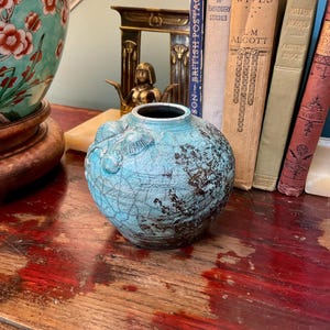 Jarrón de cerámica Raku en color turquesa con diseño de concha.