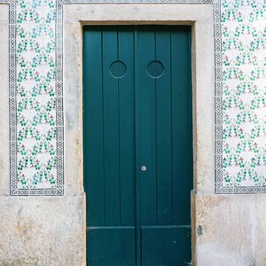 May include: A teal green double door with a white trim and a white and green tiled wall behind it.