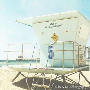 May include: A white lifeguard stand with a blue number "15" on the side. The stand has a sign that reads "Keep Off No Lifeguard On Duty".