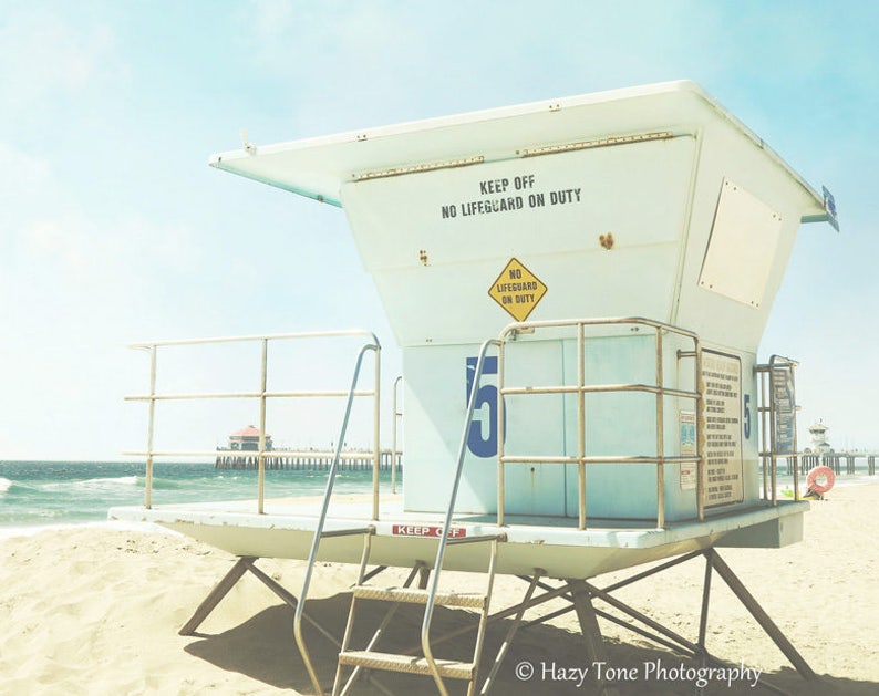 May include: A white lifeguard stand with a blue number "15" on the side. The stand has a sign that reads "Keep Off No Lifeguard On Duty".