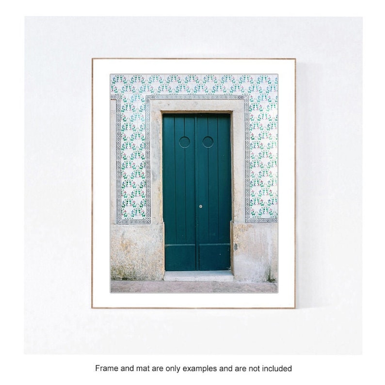 May include: A teal green door with two panels and a circular handle. The door is framed by a white stone archway and surrounded by white and green patterned tiles.