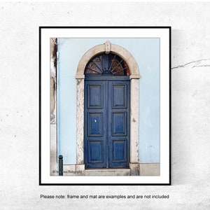 May include: A blue double door with a decorative arched window above it. The door is set in a light blue wall with white trim.