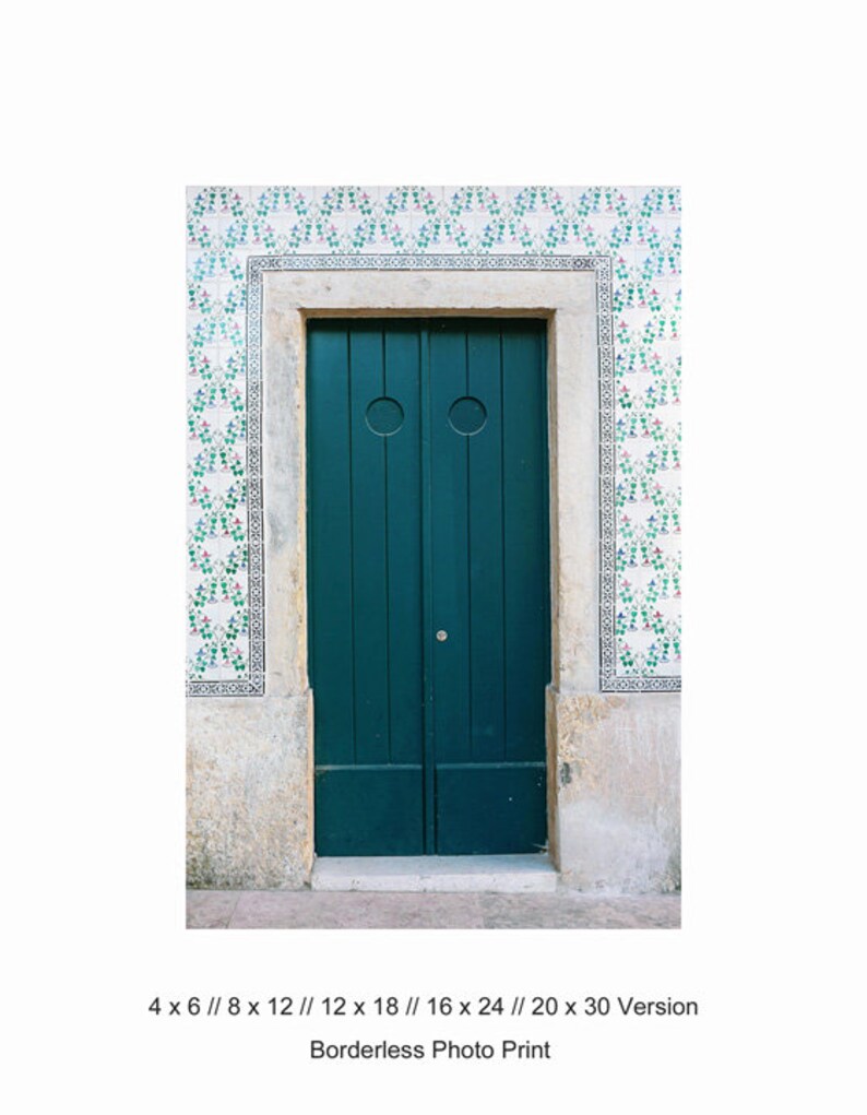 May include: A teal green double door with two circular door knockers, set in a stone doorway with a white and green tiled wall.