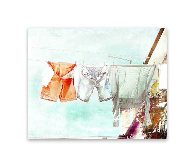 May include: A watercolor painting of clothing hanging on a clothesline. The clothing includes a pair of orange shorts, a pair of blue denim shorts, and a light gray shirt.