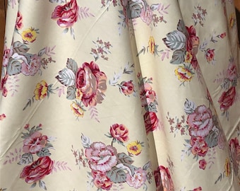 May include: A cream-colored fabric with a floral pattern featuring pink, red, and yellow roses. The fabric has a subtle sheen and a soft texture.