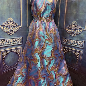 May include: A strapless floor-length gown featuring a vibrant iridescent blue and purple fabric with a swirling metallic gold pattern. The dress is cinched at the waist with a decorative belt composed of interconnected circular metal rings.