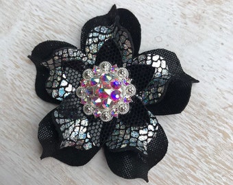 May include: A black fabric flower with a silver iridescent finish and a large iridescent rhinestone center.