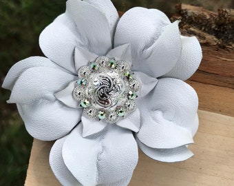 May include: A white leather flower with a silver and iridescent rhinestone embellishment in the center.