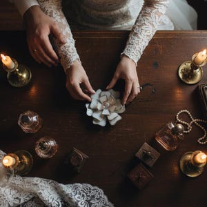 Puede incluir: Un letrero de madera r&uacute;stico blanco con la palabra "Welcome" escrita a mano. El letrero tiene un aspecto envejecido y un elemento floral decorativo. El fondo es una imagen borrosa de una casa.