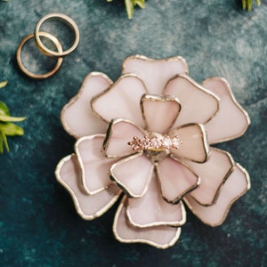 Suft lilac stained-glass flower ring dish displayed on a cool matte surface with subtle greenery. Soft pastel petals capture feminine wedding trends, while the ring nestled within makes it ideal for bridal keepsakes, heirloom gifting, or an elegant ring-bearer alternative.