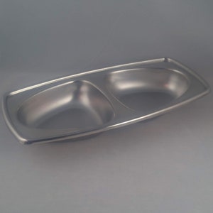 Könnte beinhalten: Eine silberne Servierplatte mit zwei Abschnitten in rechteckiger Form. Die Platte ist aus Metall und hat eine glatte, glänzende Oberfläche.