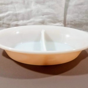 May include: A white divided baking dish with two sections. The dish has a light peach colored rim and two handles.