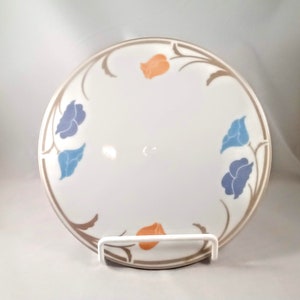 Könnte beinhalten: Ein weißer Keramikteller mit braunem Rand und Blumenmuster. Die Blumen sind blau, hellblau und orange.