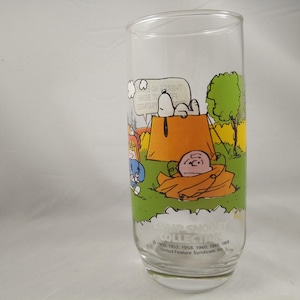 May include: A clear glass with a Peanuts camping scene. Snoopy is in a tent saying "There's no being too prepared".  The glass has the text "Camp Snoopy Collection 1950, 1952, 1953, 1958, 1960, 1965, 1968 United Feature Syndicate, Inc."