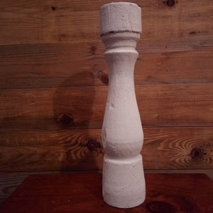 Pode incluir: Castiçal de madeira pintado de branco com um design canelado. O castiçal tem uma base redonda e uma parte superior cilíndrica.