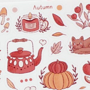 May include: A set of autumn-themed stickers featuring a red teapot, a pumpkin, a cat, a candle, mushrooms, leaves, and apples. The stickers are on a white background and have a hand-drawn style.