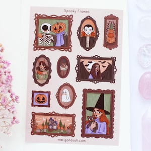 Peut inclure: Une planche d'autocollants intitulée "Spooky Frames" présentant diverses illustrations sur le thème d'Halloween dans des cadres ornés. Les dessins incluent un squelette avec une tête de citrouille, un vampire, une sorcière avec un chat et une maison hantée. Le site web de l'artiste est visible.