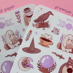 May include: Two sheets of stickers with a witchy theme. The stickers feature illustrations of a ghost reading a book, a crow on a log, a witch's hat, a crystal ball, and other mystical elements. The text "normal paper" and "premium paper" is visible.