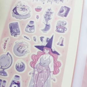 Puede incluir: Una hoja de pegatinas con una bruja de pelo rosa y un sombrero morado, un libro con el texto "Moon Magic Spells", un gato en una nube, una botella de poci&oacute;n y otros elementos m&aacute;gicos. Las pegatinas est&aacute;n sobre un fondo rosa.