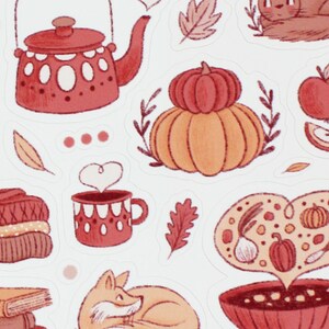 May include: A set of autumn-themed stickers featuring illustrations of a teapot, a pumpkin, a bowl of soup, a fox, a sweater, a mug of hot cocoa, and apples. The stickers are in shades of red, orange, and brown.