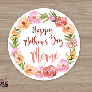 May include: A round white sticker with a watercolor floral wreath in shades of pink, orange, and green. The text "Happy Mother's Day Mémé" is written in the center of the sticker.