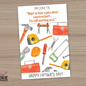 May include: A white card with a watercolour illustration of construction tools, including a hammer, saw, wrench, tape measure, and toolbox. The card has the text "DAD JOKE #3: "Want to hear a joke about construction?... I'm still working on it." HAPPY FATHER'S DAY!"