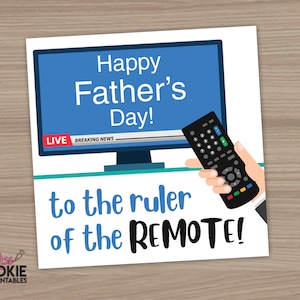 Op de afbeelding: Een Vaderdagkaart met een blauw televisiescherm met de tekst "Happy Father's Day!". De kaart bevat de tekst "to the ruler of the REMOTE!" en een hand die een afstandsbediening vasthoudt. De achtergrond is van hout.