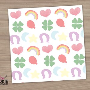 以下が含まれることがあります： ピンクのハート、緑の四つ葉のクローバー、虹、紫の馬蹄形、黄色の星、薄い青の三日月が繰り返しパターンで描かれた白い背景です。