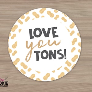 May include: Round white sticker with a peanut pattern border. The sticker has the text "LOVE you TONS!" in black and gold lettering.