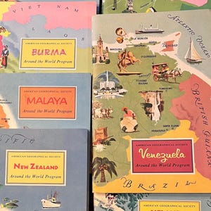 May include: A collection of vintage travel books from the American Geographical Society's "Around the World Program." The covers feature colorful illustrations and country names like Bahamas, Burma, Malaya, New Zealand, and Venezuela.