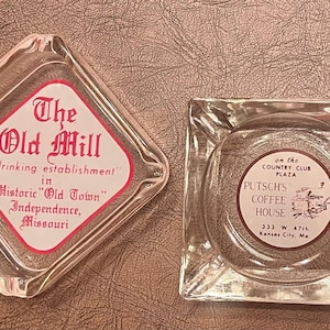 May include: Two vintage glass ashtrays. One is diamond-shaped with the text "The Old Mill" and "a drinking establishment" in Independence, Missouri. The other is square with "PUTSCH'S COFFEE HOUSE" printed on it.