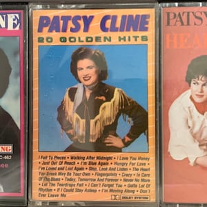 May include: Three cassette tapes featuring Patsy Cline. The first tape is titled "Patsy Cline at her Best" and features a photo of Patsy Cline in black and white. The second tape is titled "Patsy Cline 20 Golden Hits" and features a color photo of Patsy Cline in a western-style shirt. The third tape is titled "Patsy Cline Heartache" and features a color photo of Patsy Cline in a red outfit.