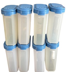 May include: A stack of eight clear plastic food storage containers with light blue lids. The containers are rectangular with rounded corners and a slightly opaque appearance. The lids have a flip-top design.