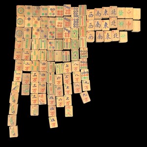 May include: A collection of rectangular light-coloured wooden Mahjong tiles arranged in a grid pattern. Each tile features hand-painted Chinese characters, numbers, and symbols in red, green, blue, and black ink, representing various suits and honours.