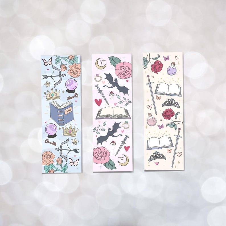 May include: Three colorful bookmarks with a fantasy theme. Each bookmark features a different design with illustrations of a dragon, a crown, a book, a sword, a heart, a butterfly, a key, a potion bottle, a moon, a rose, and other magical elements.