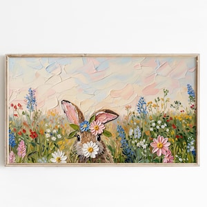 May include: A framed painting of a bunny in a field of wildflowers. The bunny has a daisy in its mouth and a flower crown. The background has a textured, pastel sky. The flowers are in shades of red, blue, pink, and yellow.