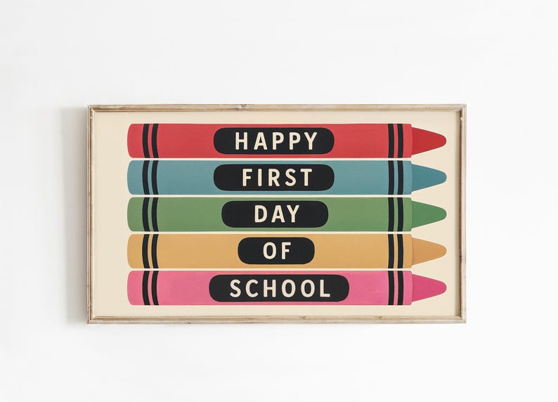 May include: A framed print featuring five colorful crayons with the words "HAPPY FIRST DAY OF SCHOOL" in white text on black ovals. The crayons are red, teal, green, yellow, and pink, set against a cream background.