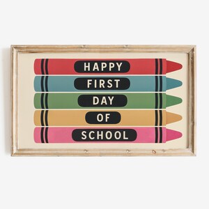 May include: A framed print featuring five colorful crayon illustrations. Each crayon has a black label with white text that reads "HAPPY FIRST DAY OF SCHOOL". The crayons are red, teal, green, yellow, and pink.