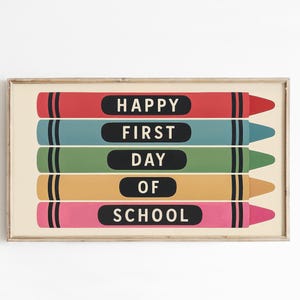 May include: A framed horizontal print featuring five stacked crayon illustrations in red, blue, green, yellow, and pink. Each crayon contains a black oval label with white text reading HAPPY FIRST DAY OF SCHOOL, with one word per crayon.