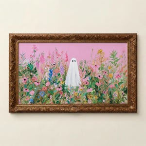 May include: A framed art print featuring a white ghost in a field of colorful flowers against a pink background. The artwork is enclosed in a decorative, ornate gold-colored frame, creating a whimsical and charming aesthetic.