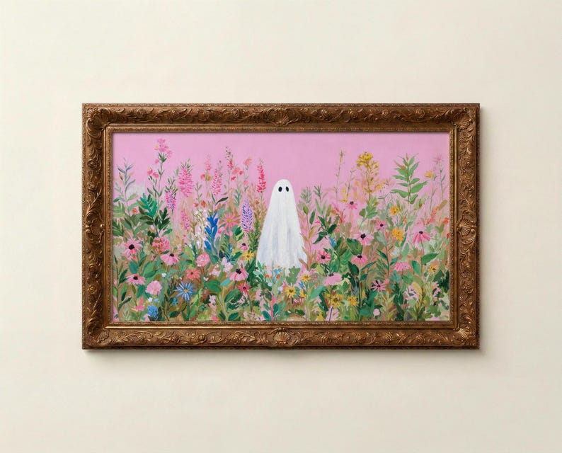 May include: A framed art print featuring a white ghost in a field of colorful flowers against a pink background. The artwork is enclosed in a decorative, ornate gold-colored frame, creating a whimsical and charming aesthetic.