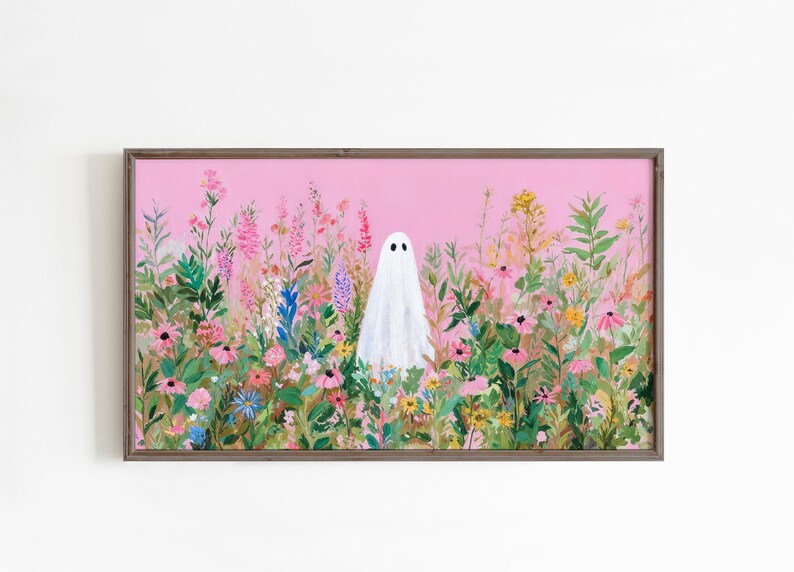 May include: A framed art print featuring a white ghost figure standing in a field of colorful wildflowers. The background is a soft pink, and the frame is a muted brown. The artwork has a whimsical, nature-inspired theme.
