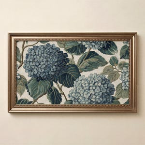 May include: A rectangular framed wall art piece featuring a woven textile design of blue hydrangea flower clusters and dark green leaves on a light cream background, enclosed in a metallic bronze frame with a beaded inner edge detail.