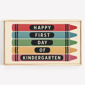 May include: A framed print featuring five colorful crayon illustrations. Each crayon is a different color: red, teal, green, yellow, and pink. The text on the crayons reads "HAPPY FIRST DAY OF KINDERGARTEN."