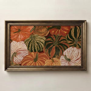May include: A rectangular framed painting featuring a collection of pumpkins in various colors including orange, dark green, and white with striped patterns. The artwork is enclosed in a metallic bronze-toned frame with a beaded inner edge detail.