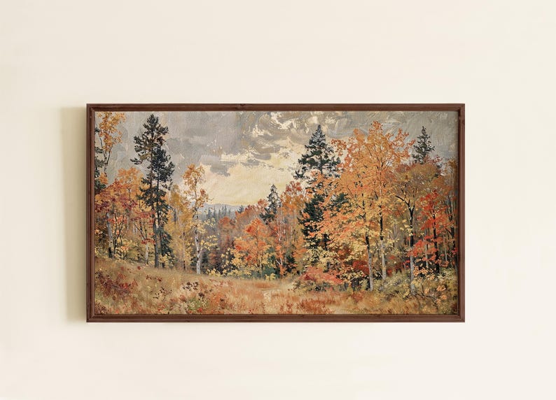May include: A rectangular landscape painting in a dark brown wooden frame depicting an autumn forest scene with orange, yellow, and red foliage on trees, dark green pine trees, and a cloudy, overcast sky above a grassy, textured foreground.