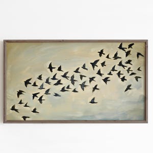 Puede incluir: Una obra de arte enmarcada que representa una bandada de pájaros negros en vuelo sobre un fondo azul claro y beige. Los pájaros están pintados en silueta, creando una sensación de movimiento y libertad. La obra está enmarcada en un marco de madera marrón.